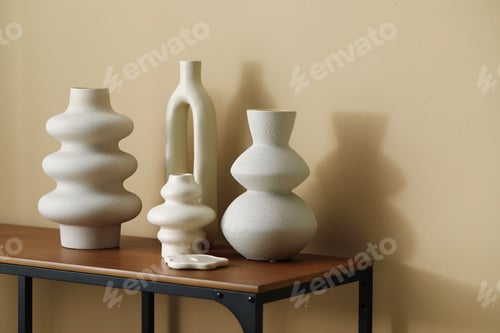 Preview: Beautiful vases on wooden table near beige wall indoors, space for text