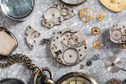 Preview: Mechanism of vintage wrist watch and gears on grey table, flat lay