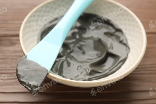 Preview: Mud therapy. Natural clay paste for facial and body care and brush on wooden table, closeup