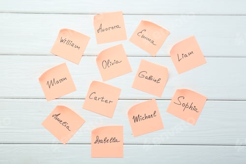 Preview: Paper stickers with different names on white wooden background, flat lay. Choosing baby's name