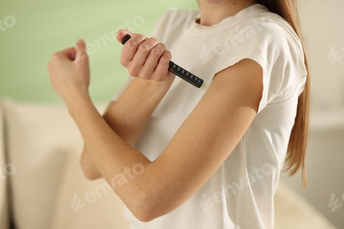 Preview: Diabetes. Woman making insulin injection into her arm with autoinjector indoors, closeup