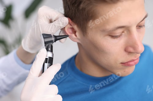Preview: Hearing test. Doctor examining man's ear with otoscope in clinic, closeup