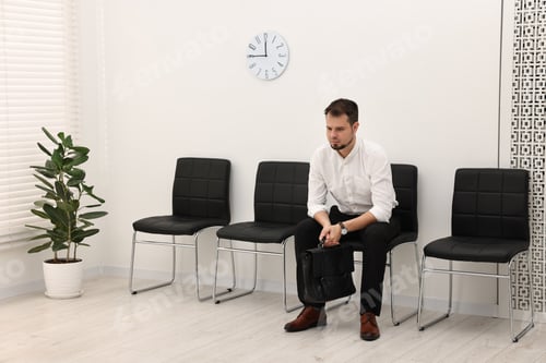 Preview: Man sitting on chair and waiting for job interview indoors