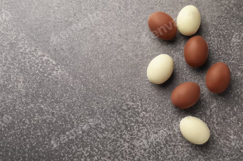Preview: Easter celebration. Many chocolate eggs on grey textured table, flat lay with space for text