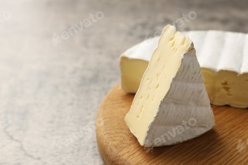 Preview: Cut delicious brie cheese on grey table, closeup. Space for text