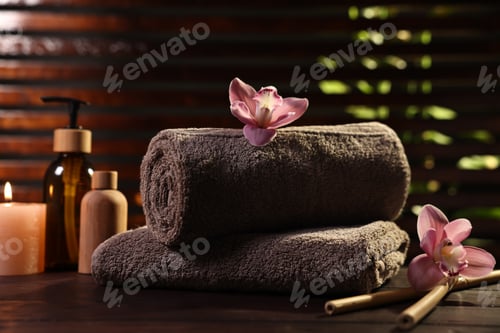 Preview: Spa composition with soft clean towels and orchid flowers on wooden table indoors, closeup
