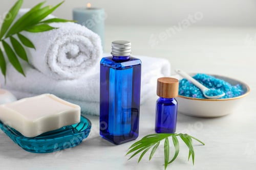Preview: Spa composition. Cosmetic products, soap, towels, sea salt and burning candle on light table