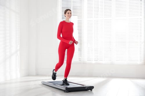 Preview: Sporty woman training on walking treadmill indoors