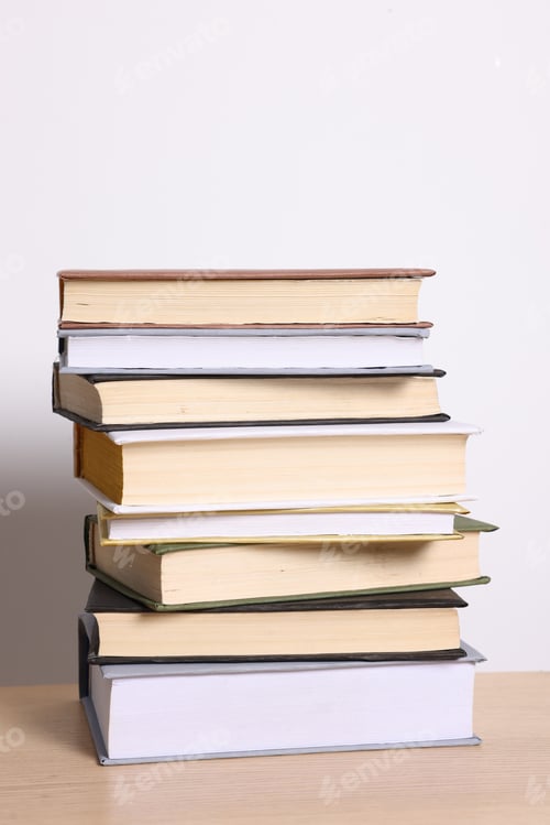 Preview: Stack of different books on wooden table against light background