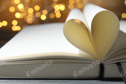 Preview: Open book with pages folded in heart shape on table against blurred lights, closeup. Bokeh effect