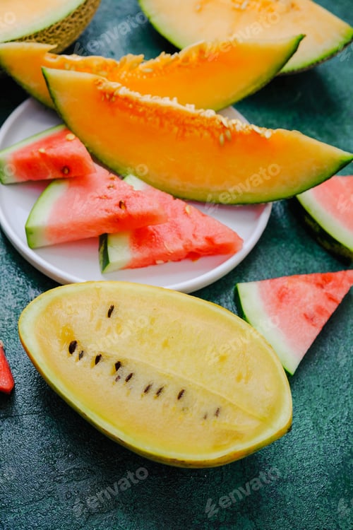 Preview: Various melon slices including cantaloupe and watermelon presented on a textured dark surface.