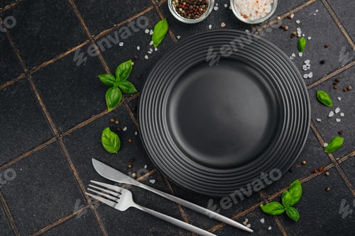 Preview: Black plate with fork and knife with basil leaves and salt