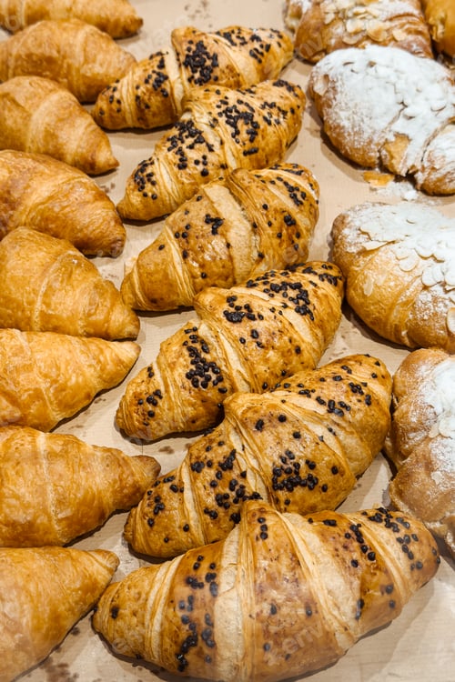 Preview: Delicious assortment of freshly baked golden croissants with chocolate chips and powdered sugar topp