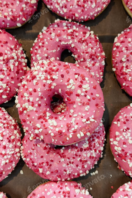 Preview: Pink glazed doughnuts with white and red sprinkles on dark surface
