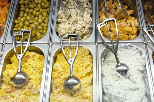 Preview: Prepared salads olives and chicken displayed at a deli counter
