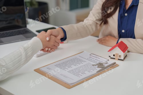Preview: Real Estate Agreement. Client and agent shaking hands over property contract in office.