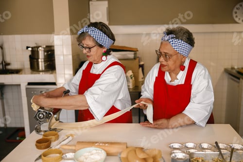 Preview: Active senior Caucasian and Black female chefs making fresh pasta in a bright professional kitchen