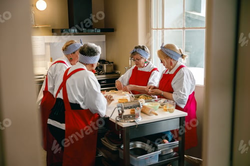 Preview: Active Caucasian senior women cooking and preparing food together in a bright kitchen