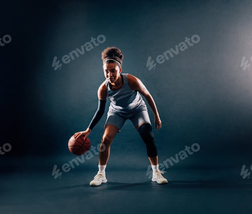 Preview: Female basketball player in team uniform bouncing a ball in studio