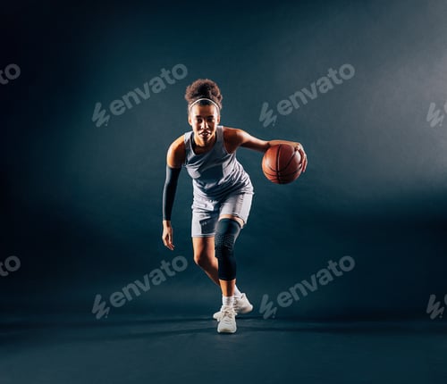 Preview: Young female professional basketball player showing skill in dribbling in a studio