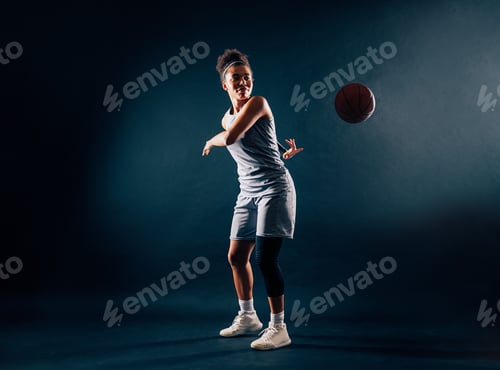 Preview: A basketball player in a team uniform throws a ball from behind her back