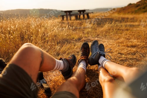 Preview: Detail of couples legs sitting on the grass relaxing while taking a hiking break