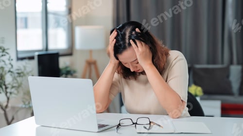 Preview: Stressed woman experiencing headache working from home