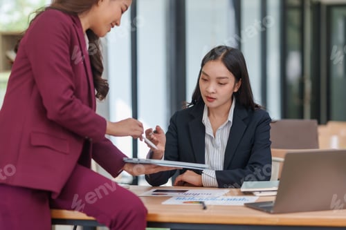 Preview: Businesswomen collaborating on digital tablet in office meeting