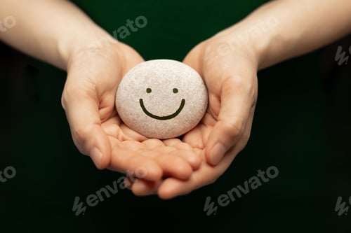 Preview: Hands holding smiling pebble,emotional support, positive mindset and mental health wellness