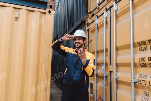 Preview: Happy logistics supervisor smiling at shipping port. Male industrial engineer touching hard hat with