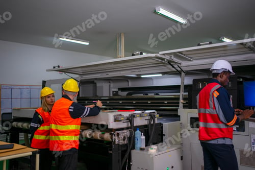 Preview: Three Factory Workers at Industrial Machinery in Manufacturing Plant