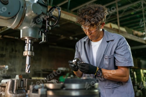 Preview: Engineer Holding Metal Component at Factory Workbench