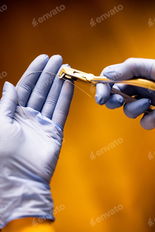 Preview: Dentist using orthodontic pliers for archwire adjustment during braces treatment procedure