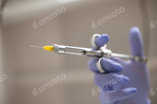 Preview: Carpule syringe held in gloved hand for dental anesthesia injection