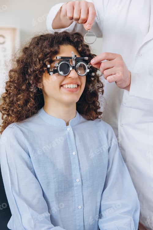 Preview: Optometrist adjusting trial frame for young woman undergoing a thorough vision examination and ophth