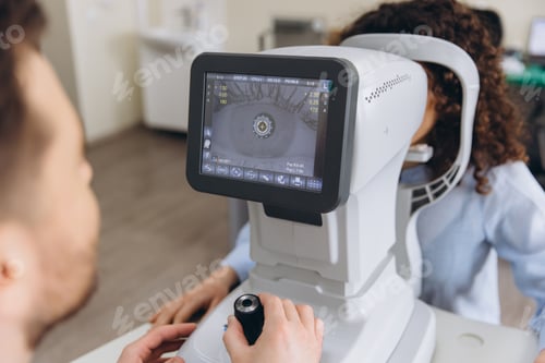 Preview: Optometrist using autorefractor machine for eye exam on patient in modern ophthalmology clinic