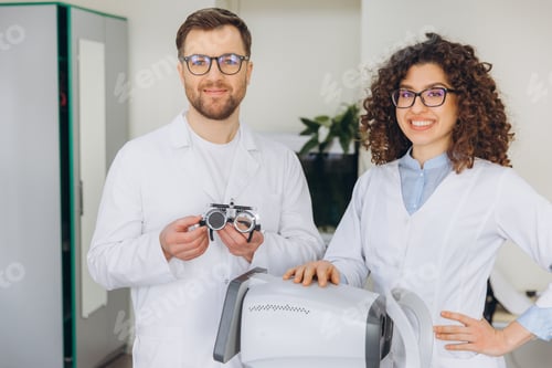 Preview: Optometrists team smiling in a modern ophthalmology clinic with phoropter and refraction equipment
