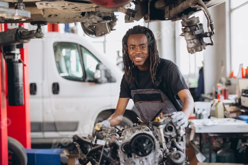 Preview: African american man mechanic smiling, wearing coverall, standing in auto service garage, working on