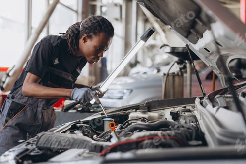 Preview: African american technician fixing car engine with professional work light in automobile repair serv