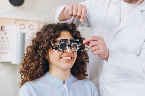 Preview: Woman having an ophthalmologist performing an eye exam with trial frames for vision correction and h