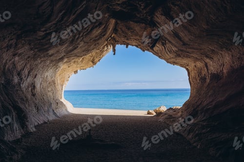 Preview: Cala Luna beach cave in Sardinia, Italy, looking out to the turquoise Mediterranean sea and sunny sk