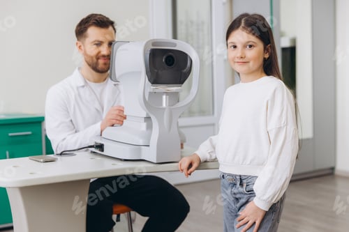 Preview: Ophthalmologist preparing autorefractor for a young girl during a pediatric vision checkup for eye h