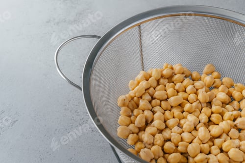Preview: Cooked chickpeas draining in metal mesh strainer on gray kitchen countertop