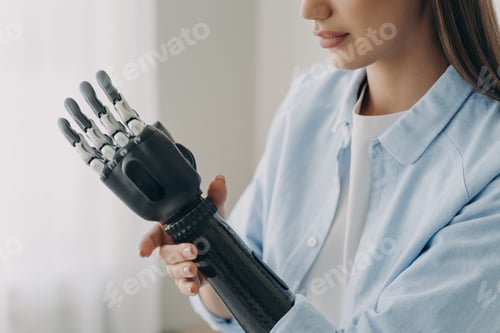 Preview: Close-up of woman adjusting prosthetic bionic arm with robotic hand in light blue shirt