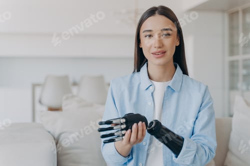 Preview: Young woman with robotic prosthetic arm sits in bright living room at home