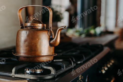 Preview: Bronze kettle in modern kitchen. Old vintage teapot on gas stove. Preparing tea. Aluminium teakettle