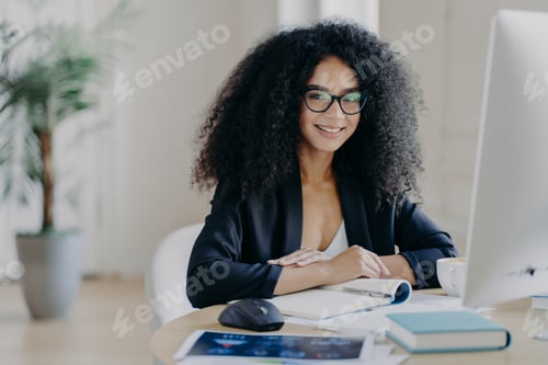 Preview: Black Female Professional with Afro Hair and Glasses Working at Computer Desk in Modern Bright Offic