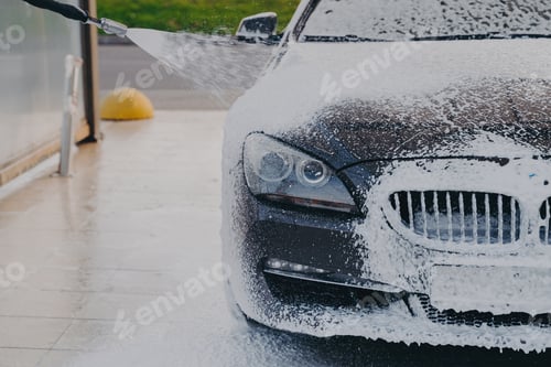 Preview: Dark Luxury Sedan Being Washed with High-Pressure Foam Spray at Professional Car Wash Station