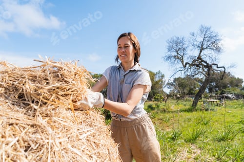 Preview: Woman adding straw mulch working in permaculture farm