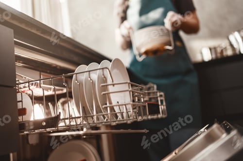 Preview: Person Unloading Clean Dishes from Dishwasher in Modern Home Kitchen